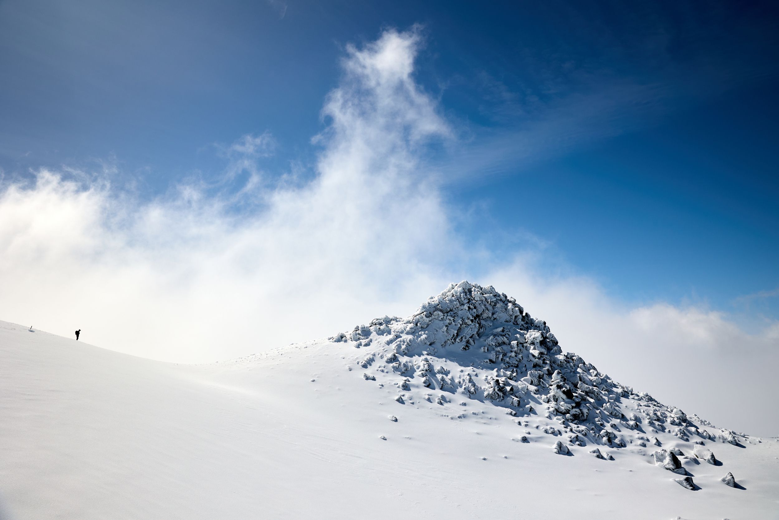 A person walking through the snowfield looking across at Fantams peak